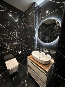 a black bathroom with a sink and a mirror at Room Studio in Tirana