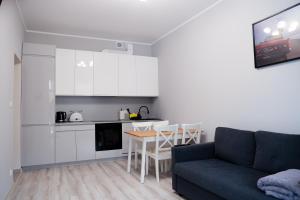 a kitchen and a living room with a couch and a table at Apartament Solankowe Zacisze Inowrocław in Inowrocław