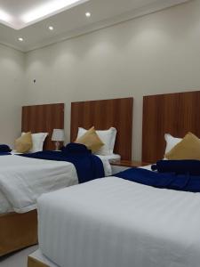 a hotel room with two beds with blue and yellow pillows at فندق منازل الضيف in Al Madinah