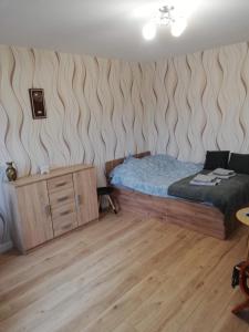 a bedroom with a bed and a wooden dresser at Emilka 2 in Suwałki