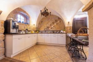 a large kitchen with white cabinets and a stone wall at Pension Bauernhaus Vetter in Kurort Gohrisch