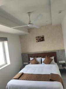 1 dormitorio con 1 cama y ventilador de techo en Signum Cityscapes The Royal Castle Plaza, en Rajkot