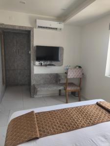 1 dormitorio con 1 cama, TV y silla en Signum Cityscapes The Royal Castle Plaza, en Rajkot