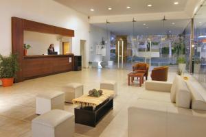 a woman is standing in a lobby with a couch and chairs at Hotel El Sauce in Santa Rosa de Calamuchita
