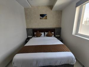 1 dormitorio con 1 cama grande en una habitación con ventana en Signum Cityscapes The Royal Castle Plaza, en Rajkot