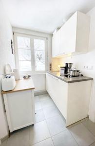 eine Küche mit weißen Schränken und weißen Fliesenböden in der Unterkunft Apartment Rose in Forbach