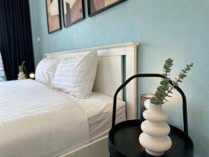 a white vase on a table next to a bed at Gloria’s Home in Kamala Beach