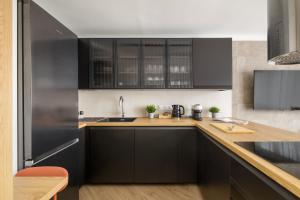 eine Küche mit schwarzen Schränken und einem Kühlschrank aus Edelstahl in der Unterkunft City Center Apartment near Park Saski by ECRU in Warsaw WWA63 in Warschau