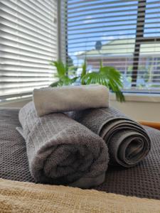 a pile of towels on a bed with a window at Beautiful haven near airport! in Christchurch