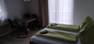 Cette chambre comprend 2 lits, une table et une fenêtre. dans l'établissement Pension Steiner, Matrei am Brenner 18b, 6143 Matrei am Brenner, à Mühlbachl