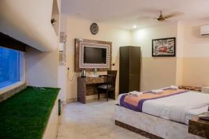 a bedroom with a bed and a desk and a television at Hotel Airport City Near Delhi International Airport in New Delhi