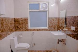 a bathroom with a toilet and a sink and a window at Hotel Airport City Near Delhi International Airport in New Delhi