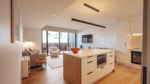 a kitchen with white cabinets and a living room at Beautiful urban apartment 4 in Nelson