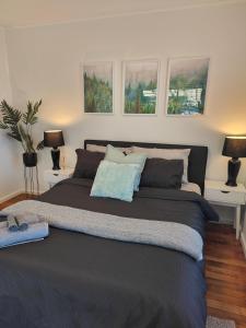 um quarto com uma cama grande, 2 candeeiros e 2 mesas em Beautiful haven near airport! em Christchurch