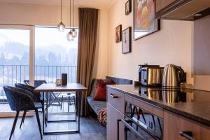 a kitchen and living room with a table and a balcony at Brixental Suites Hopfgarten by ALPS RESORTS in Hopfgarten im Brixental