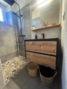 a bathroom with a sink and a shower with baskets at Les Gîtes du Saro in Chabestan