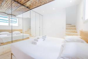 a white bedroom with two beds and a mirror at Lovely flat in the 16th arrondissement not far from the Trocadéro in Paris