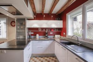 cocina con armarios blancos y paredes rojas en La Belonnerie - Grande maison pour 13, en Varrains