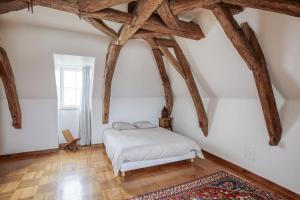 1 dormitorio con paredes blancas y vigas de madera en La Belonnerie - Grande maison pour 13, en Varrains