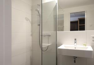 bagno bianco con doccia e lavandino di Tools Hotel Laichingen a Laichingen