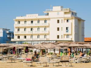 a hotel with tables and chairs and umbrellas on the beach at Hotel Tokio Village in Lido di Savio