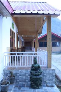 uma estátua verde sentada em frente a um edifício em Mount Vista Huts And Cafe em Kasol