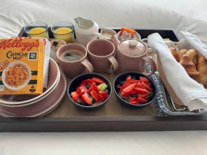 a tray of food with cups and bowls of fruit and pastries at East Beach Guest House in Littlehampton