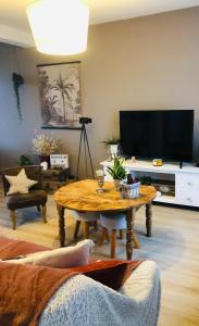 a living room with a table and a flat screen tv at Maison paisible in Niort