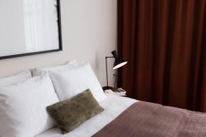 1 dormitorio con 1 cama con almohadas blancas y lámpara en Plesman Residences en Scheveningen