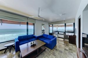 a living room with a blue couch and the ocean at Hikka Tranz by Cinnamon in Hikkaduwa