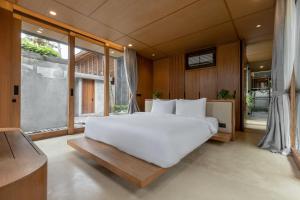 - une chambre avec un grand lit blanc et une grande fenêtre dans l'établissement Rumah Amadangi, à Tanah Lot