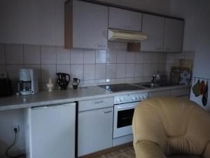 a kitchen with white appliances and a yellow chair at NEU! See-Ferienwohnung 2 in Großmöhlau +15 photos