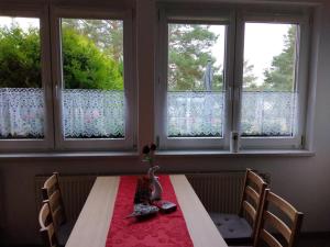 a dining room table with two chairs and two windows at NEU! See-Ferienwohnung 1 in Großmöhlau +15 photos