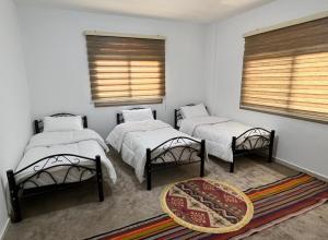 two beds in a room with two windows and a rug at Eman house in Wadi Musa