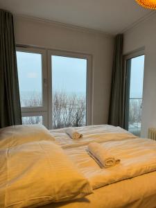 a bed with two towels on it in a room with windows at Apartament przy plaży 9 in Mielno