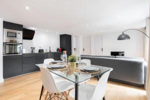 Il comprend une cuisine et un salon avec une table en verre et des chaises blanches. dans l'établissement Old Lille - Lovely typical apartment!, à Lille
