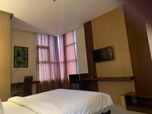 ein Hotelzimmer mit einem Bett und einem TV in der Unterkunft LYNT Hotel in Jakarta