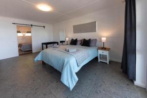 a bedroom with a large bed with a blue blanket at 'Seaside Cottage', Sleeps 4 with a 3 minute walk from the beach! in Cape Town +25 photos