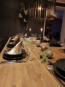 a long wooden table with plates and wine glasses at Andenes Sentrum Apartment in Andenes