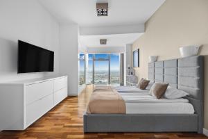 a bedroom with a large bed and a flat screen tv at 30th+ Floor Apartments in Sky Tower in Wrocław
