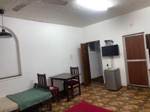 Zimmer mit einem Tisch, Stühlen und einem TV in der Unterkunft Pihuu hotel in Calangute