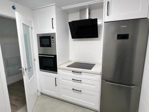 a kitchen with white cabinets and a stainless steel refrigerator at Jardines del Porvenir 4 in Puerto Real