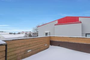 Stay Iceland apartments - U 16 في ريكيافيك: شرفة مغطاة بالثلج مع مبنى احمر وبيضاء