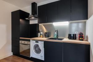 a kitchen with black cabinets and a washing machine at Lille Grand Place - 1 bedroom apartment in Lille