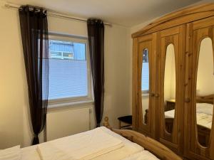 a bedroom with a wooden cabinet and a window at Ferienwohnung Seekuh in Esens +15 photos