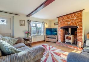 a living room with a brick fireplace and a tv at Valentine Cottage in Snape