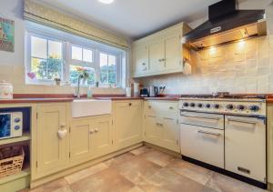 a kitchen with white cabinets and a sink at Valentine Cottage in Snape