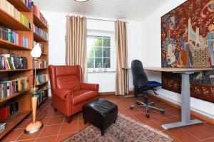a library with a chair and a desk and bookshelves at Ferienhaus Dohlennest in Carolinensiel