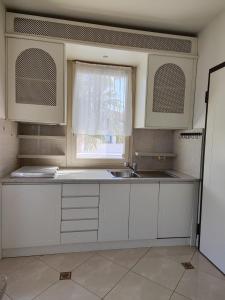 cocina blanca con fregadero y ventana en Villa Azzurra Depandance con piscina, en Desenzano del Garda