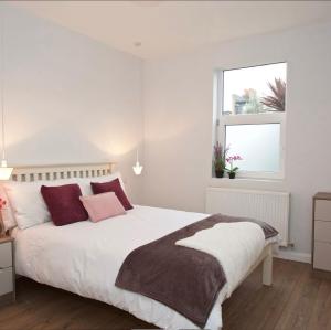 una camera bianca con un grande letto con cuscini rossi di Beautiful 2-Bed Apartment in London a Londra